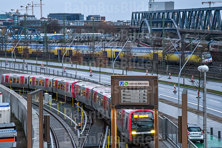 Eine U-Bahn der Linie U4 erreicht den Bahnhof Elbbrücken im Hamburger Hafen - im Hintergrund ein Metronom-Regionalzug